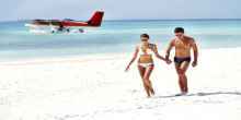 Attractive young couple walking on the beach with a seplane floating in the background