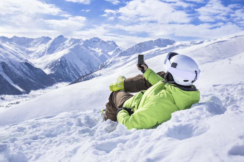 Junger Mann mit Smartphone im Schnee
