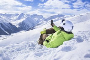 Junger Mann mit Smartphone im Schnee